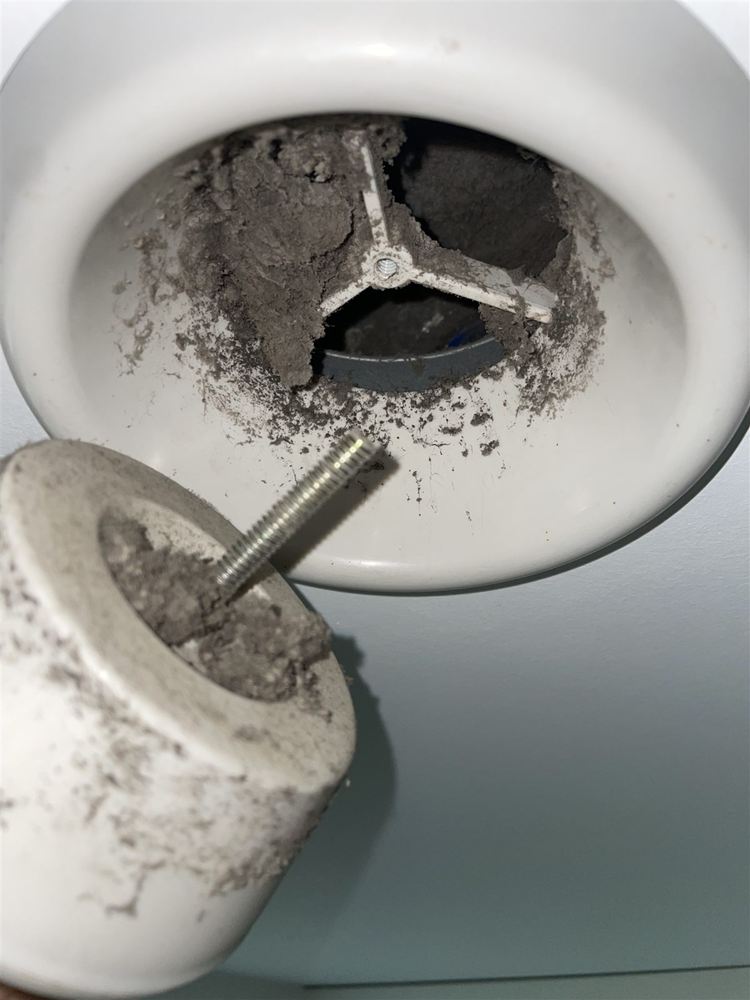 Tellerventil an der Decke vor der Reinigung: Öffnung und abgenommener Ventilteller voller Staub